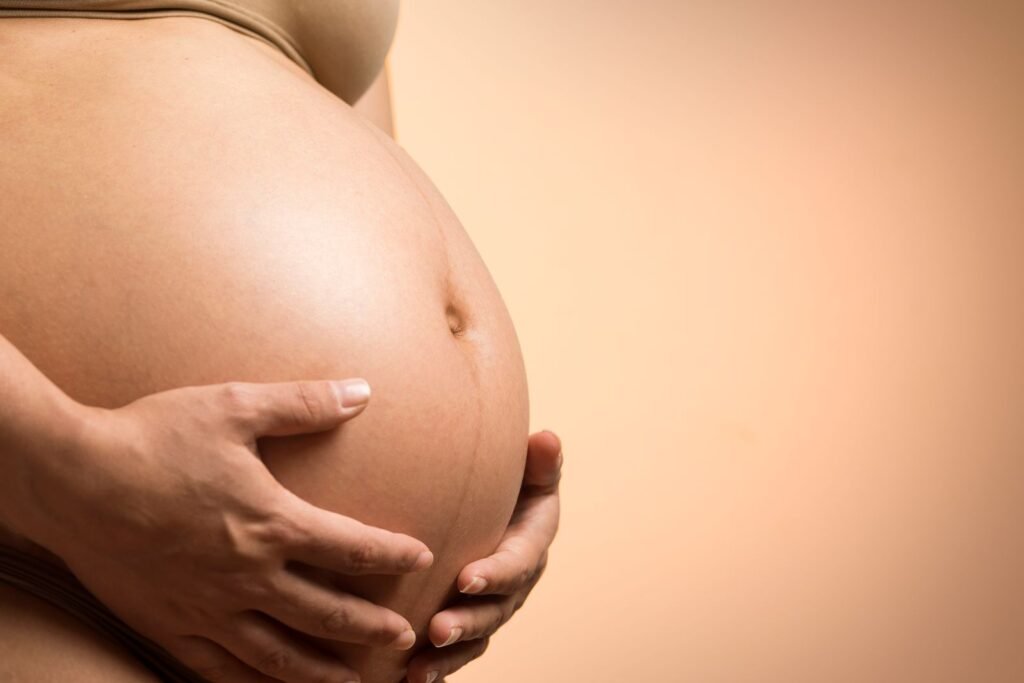 Mani che accarezzano il pancione in gravidanza, luce calda