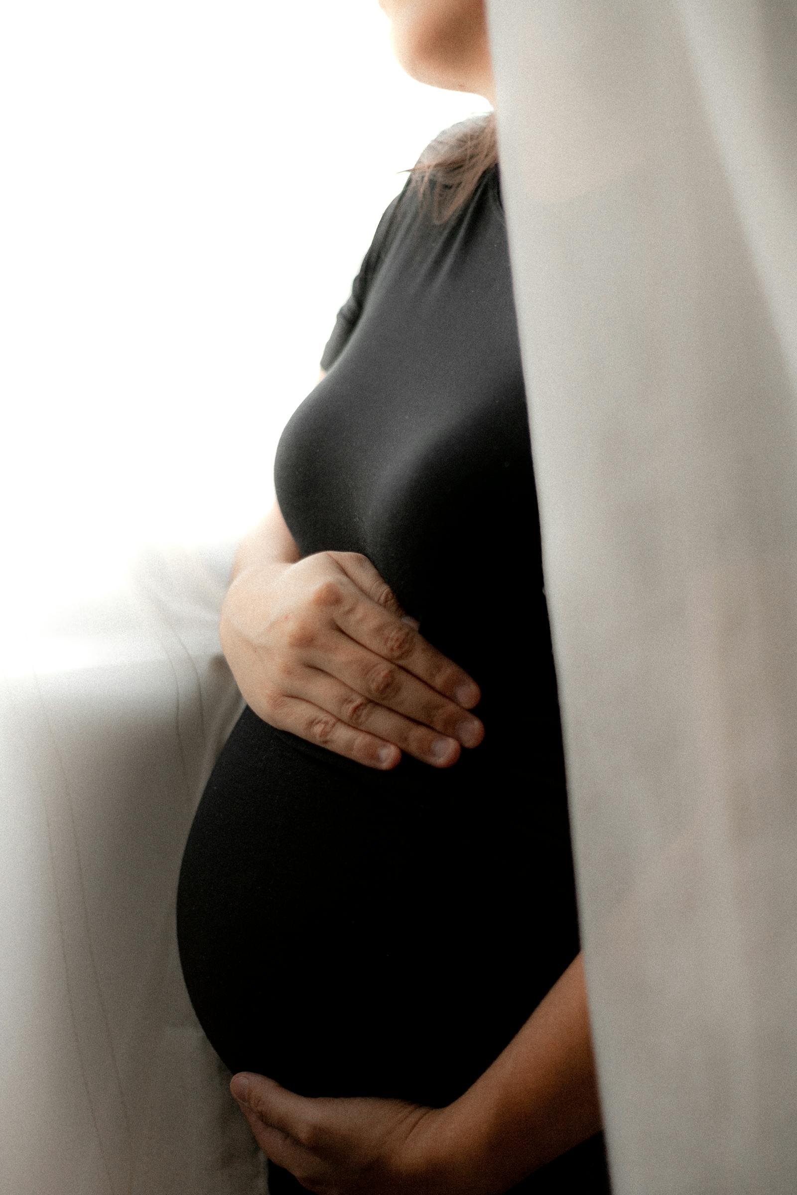 Donna in gravidanza alla finestra, luce delicata