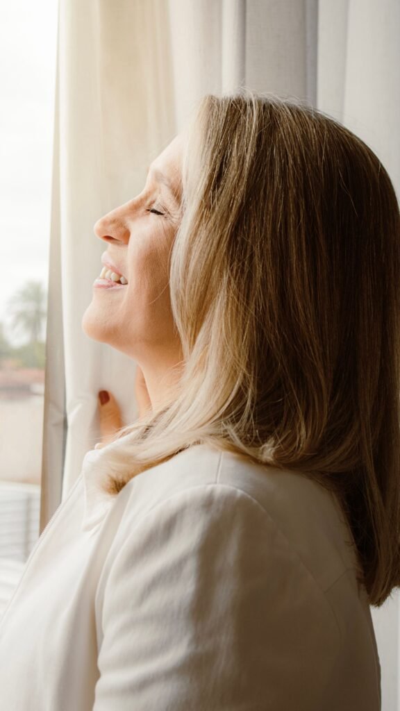 Donna sui cinquant'anni che sorride alla luce della finestra